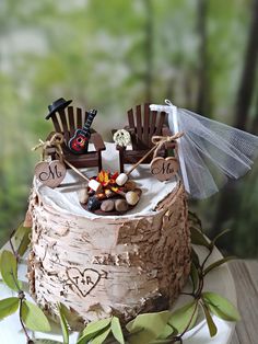 a wedding cake decorated with wooden chairs and decorations on top of a white plate in front of trees