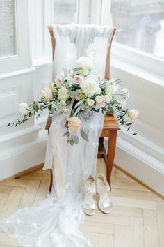 a bouquet of flowers sitting on top of a wooden chair next to a pair of shoes