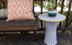 a small table with a plant on it next to a pillow