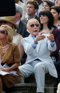 an older man and woman sitting next to each other in front of a group of people