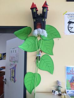 a green plant with leaves and a castle on it's head is in front of a yellow wall