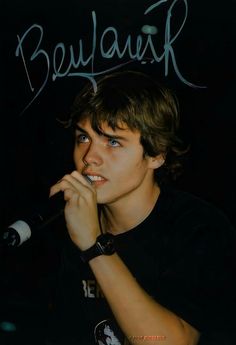 a young man holding a microphone to his mouth with the words beaulaur on it