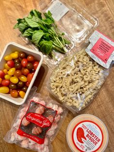 several different types of food are laid out on a wooden table, including tomatoes, pasta and spinach