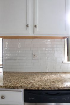 a kitchen with white cabinets and marble counter tops