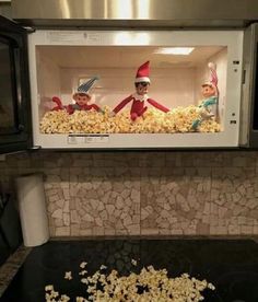 two elfs are in the microwave with popcorn