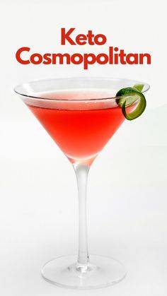 a red cocktail in a martini glass with an avocado garnish on the rim