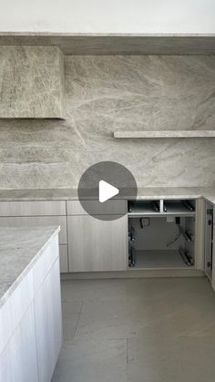 an empty kitchen with white cabinets and marble counter tops, is shown in this video