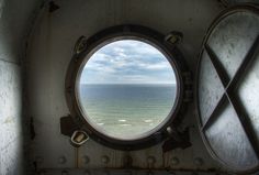 a porthole window on the side of a ship looking out at an ocean and beach