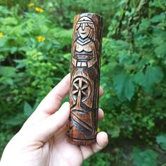 a person holding up a carved wooden object in their hand