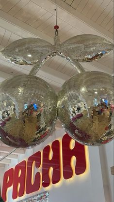 three shiny disco balls hanging from the ceiling in front of a sign that says pruch