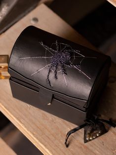 a black leather box sitting on top of a wooden table next to a pair of scissors