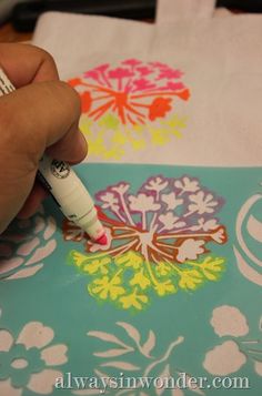 a person using a marker to draw flowers on fabric