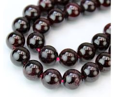 a close up of a beaded necklace on a white surface with red and black beads