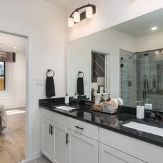 a large bathroom with double sinks and black counter tops in front of a walk - in shower