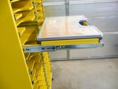 a yellow shelf with several bins on it in a storage area next to other shelves