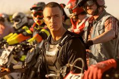 a group of men standing next to each other in front of motorbike helmets