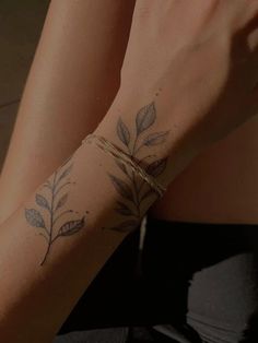 a close up of a person's arm with leaves on it and a string attached to the wrist