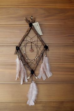 a dream catcher with feathers hanging from it's side on a wooden wall next to a pen