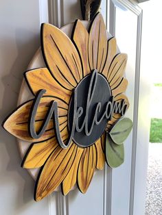 a welcome sign hanging on the side of a door with a sunflower painted on it