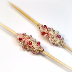 two knitting needles with beads on them sitting next to each other in front of a white background