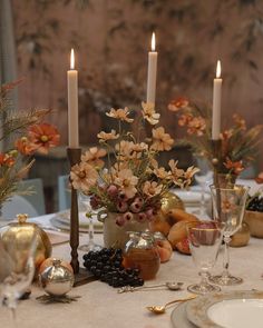 the table is set with candles and flowers in vases, plates and silverware