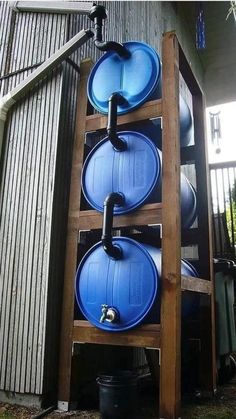 a stack of blue water tanks sitting on top of a wooden stand next to a building