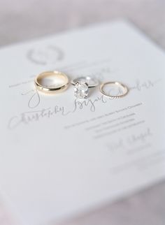 two wedding rings sitting on top of a white paper with the word marriage written in cursive writing