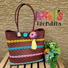 a brown bag sitting on top of a wooden bench next to a potted plant