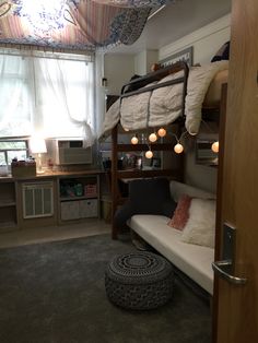 a bunk bed in a dorm room with lights hanging from it's ceiling and other items on the floor