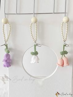 three crocheted flowers are hanging from a hook on a white wall with beads