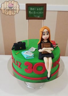 a cake with a woman sitting on top of it and holding a book in her lap