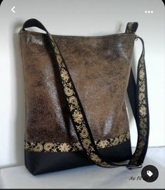 a brown and black purse sitting on top of a white table next to a wall