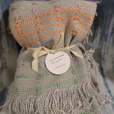 a gray and orange blanket with a tag on it