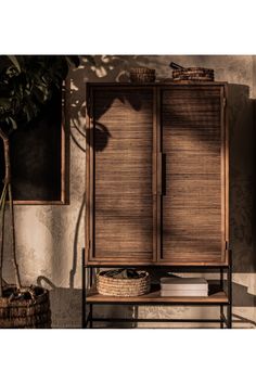 a wooden cabinet sitting next to a potted plant