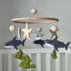 three stuffed sharks hanging from a mobile in a crib with starfishs and sea creatures