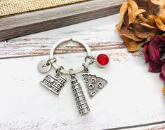 a guitar keychain with two charms attached to it, sitting next to flowers