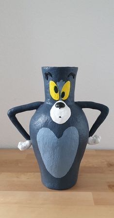 a blue vase with yellow eyes and arms