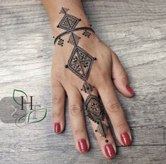 a woman's hand with a tattoo design on the left wrist and right hand