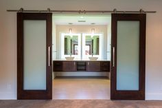 an open door leading to a bathroom with double sinks and mirrors on the wall in front of it