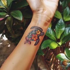 a woman's arm with a turtle tattoo on it and flowers in the middle