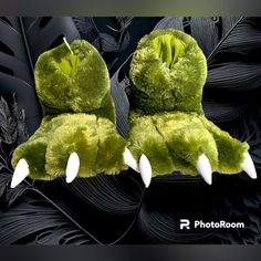 two green stuffed animals with white horns and claws on their heads, sitting next to each other