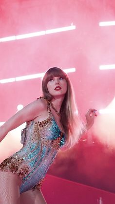 a woman with long blonde hair wearing a blue and gold dress in front of a red background