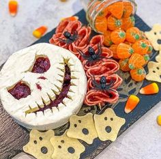 an assortment of halloween treats are arranged on a wooden board with candy and candies