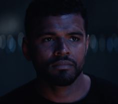 a man is staring at the camera with blurry lights in the background