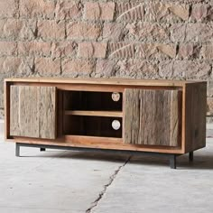 a wooden entertainment center sitting on top of a cement floor next to a brick wall