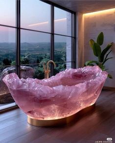 a large pink crystal bowl sitting on top of a wooden table next to a window