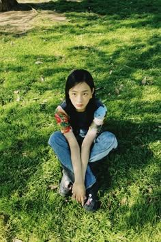 a woman sitting in the grass with her hand on her hip and looking at the camera