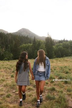 two girls walking in the grass holding hands