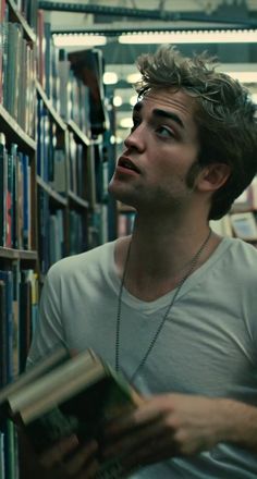 a man is looking up at the sky while reading a book in a library with bookshelves full of books