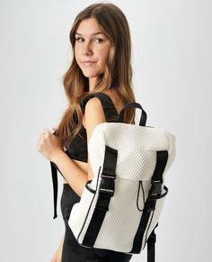 a woman with a white and black backpack is posing for the camera while holding her hand on her hip